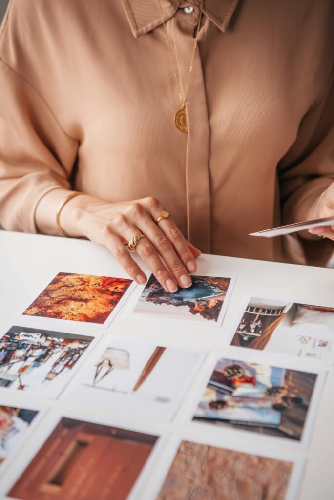 A woman organizes a collection of vibrant travel photos on a white table. Perfect for travel inspiration.